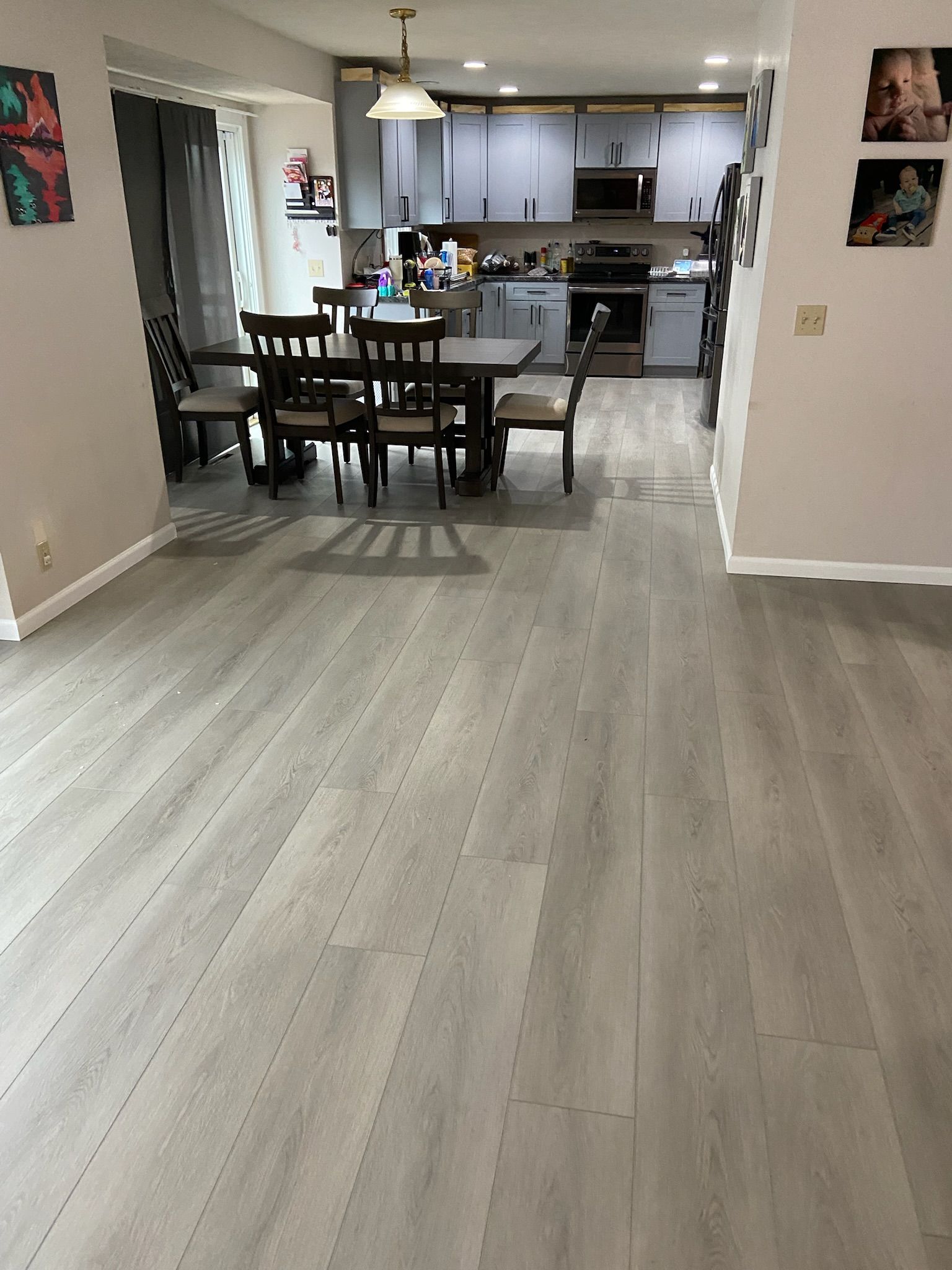 Open-concept dining and kitchen with light gray flooring and dark wood dining set.
