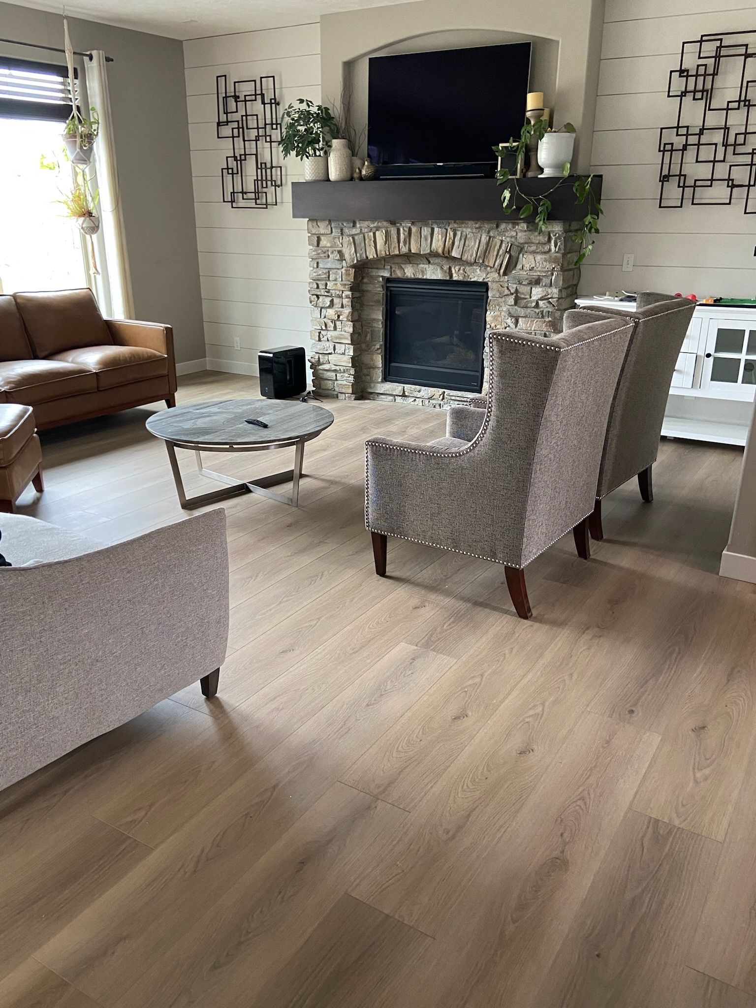 Living room with fireplace, armchairs, and light wooden floor.