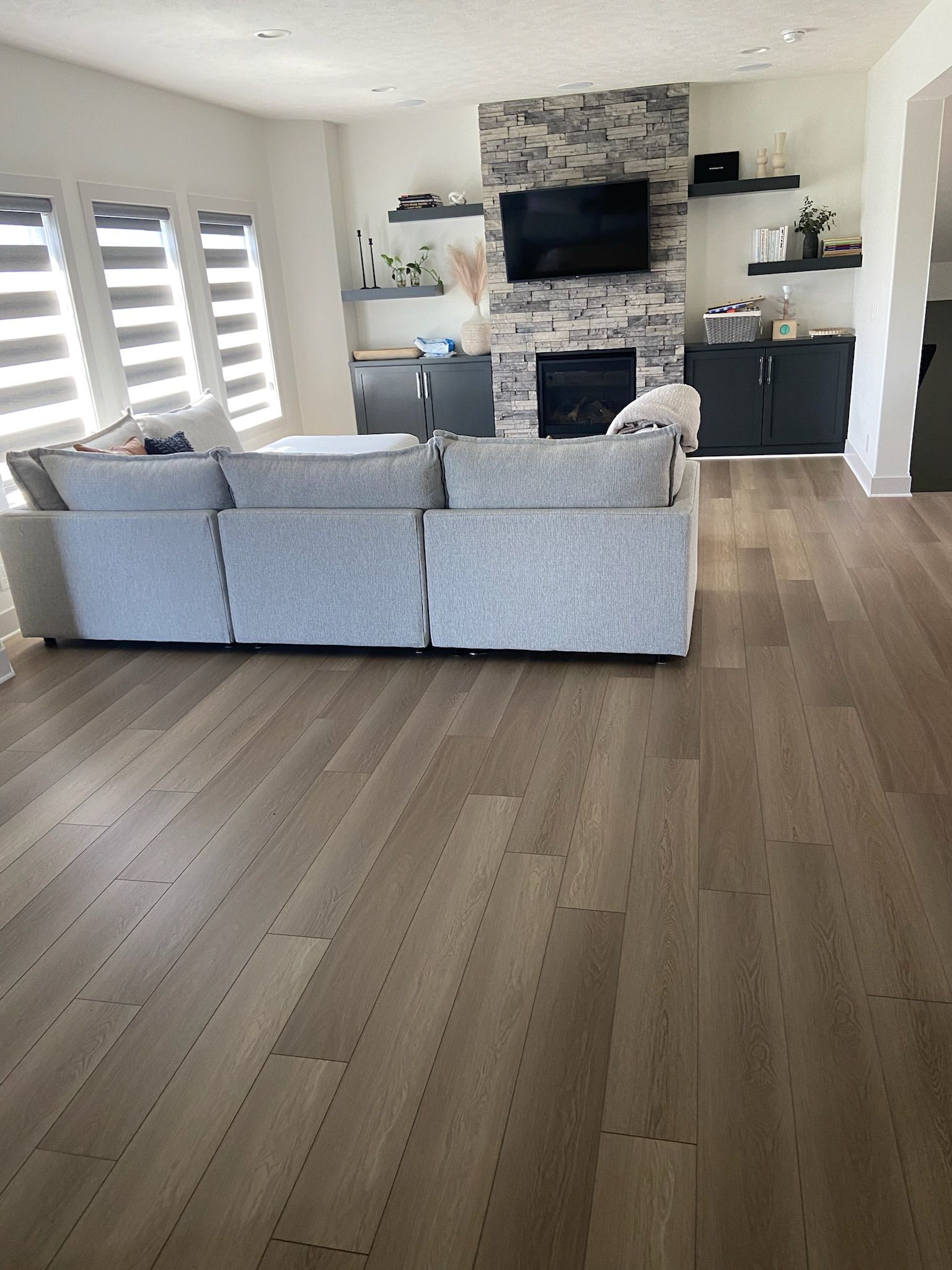 Living room with gray sofa, fireplace, and hardwood flooring.