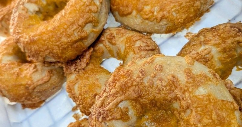 A close up of a bunch of cheese doughnuts on a plate.