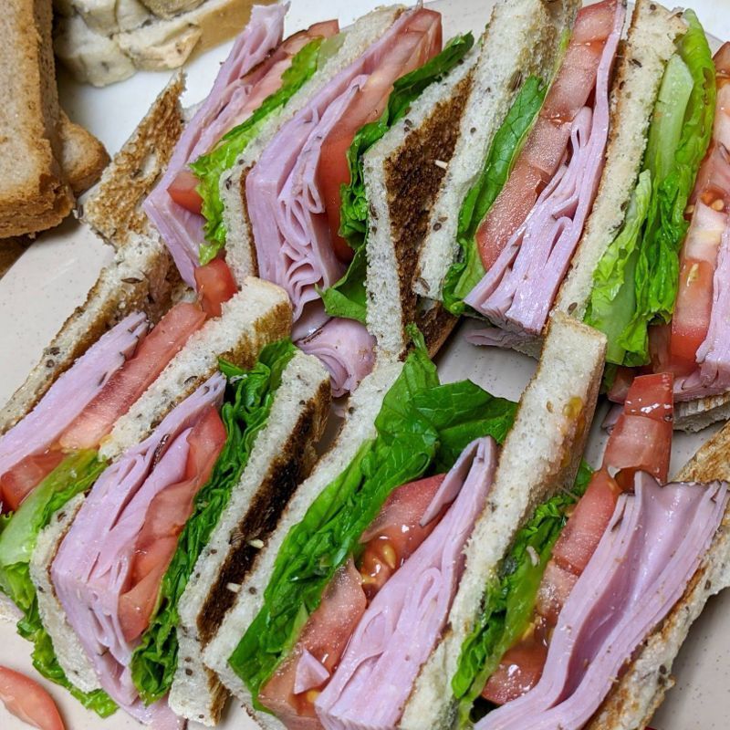 A club sandwich with ham lettuce and tomatoes on a plate