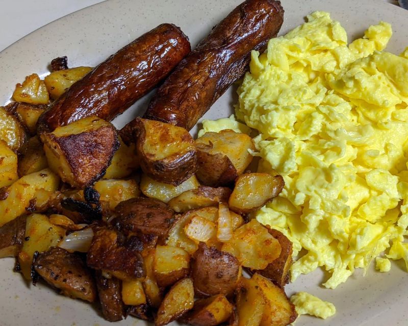A plate of food with eggs potatoes and sausages