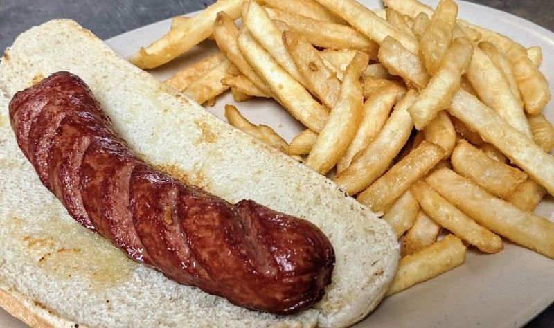 A hot dog on a bun with french fries on a plate.