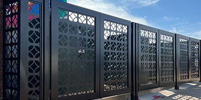 A row of black metal fences with a pattern on them.