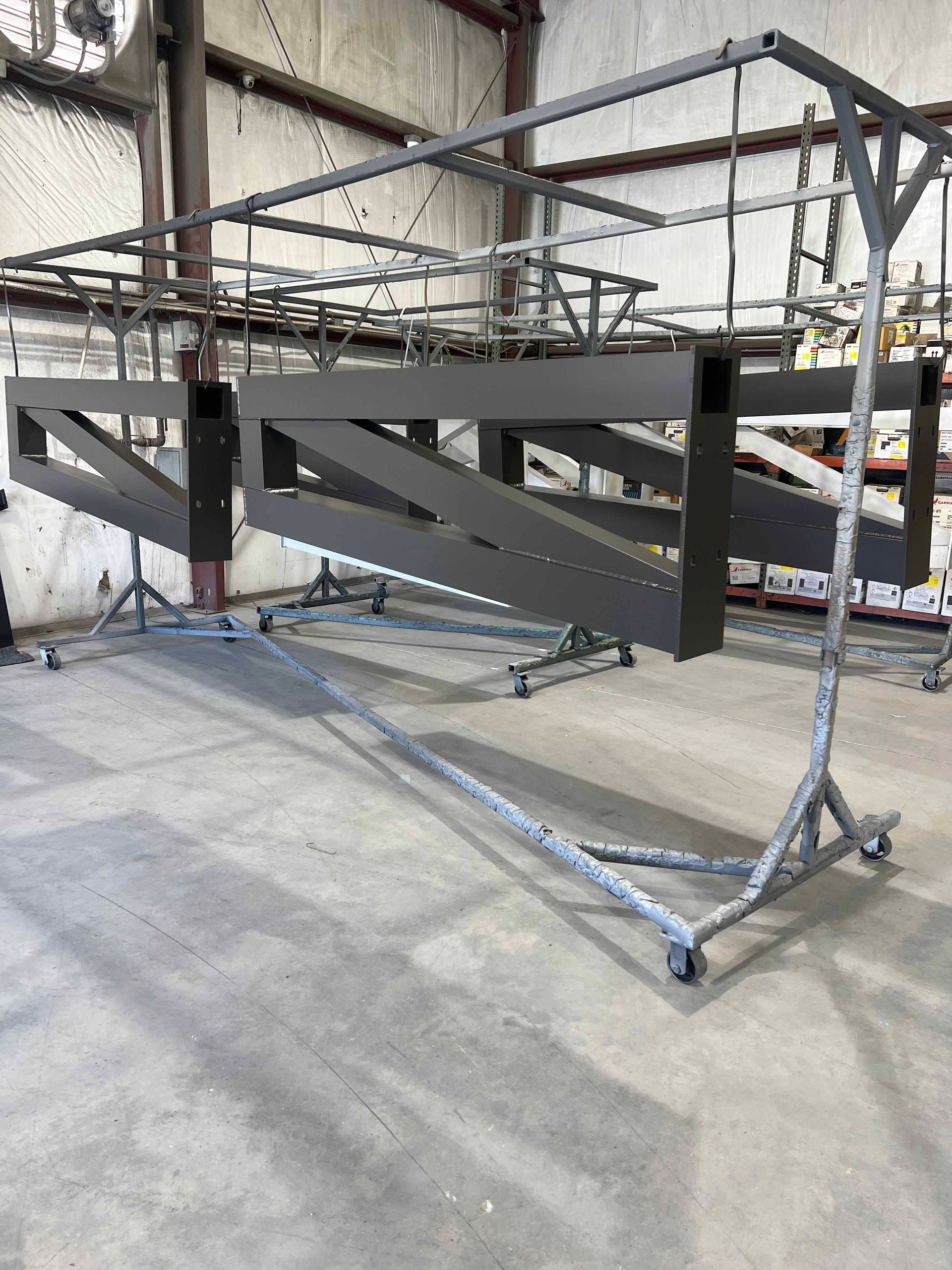 A large metal structure is sitting on a cart in a warehouse.