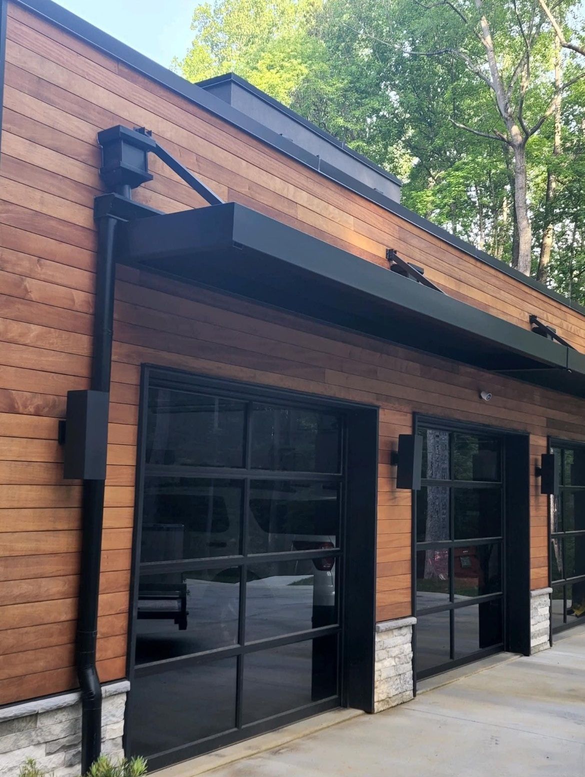 A house with a wooden siding and black garage doors