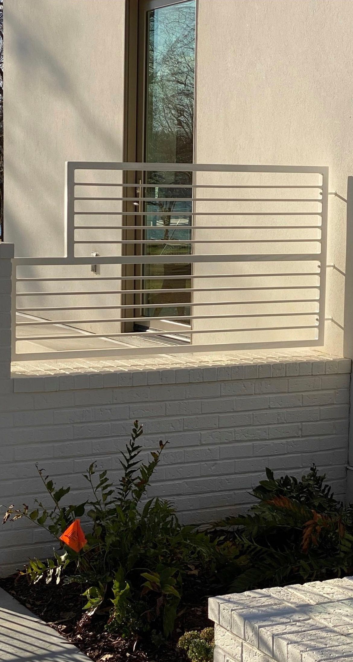 A white brick building with a balcony and a window.