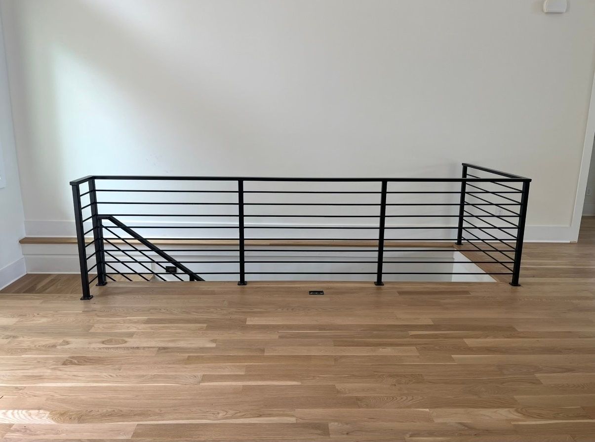 An empty room with hardwood floors and a metal railing.