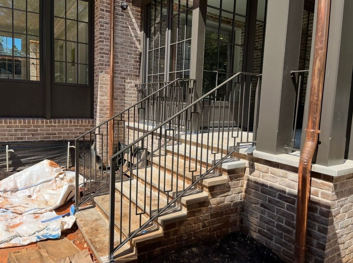 A wrought iron railing is being installed on the stairs of a house.