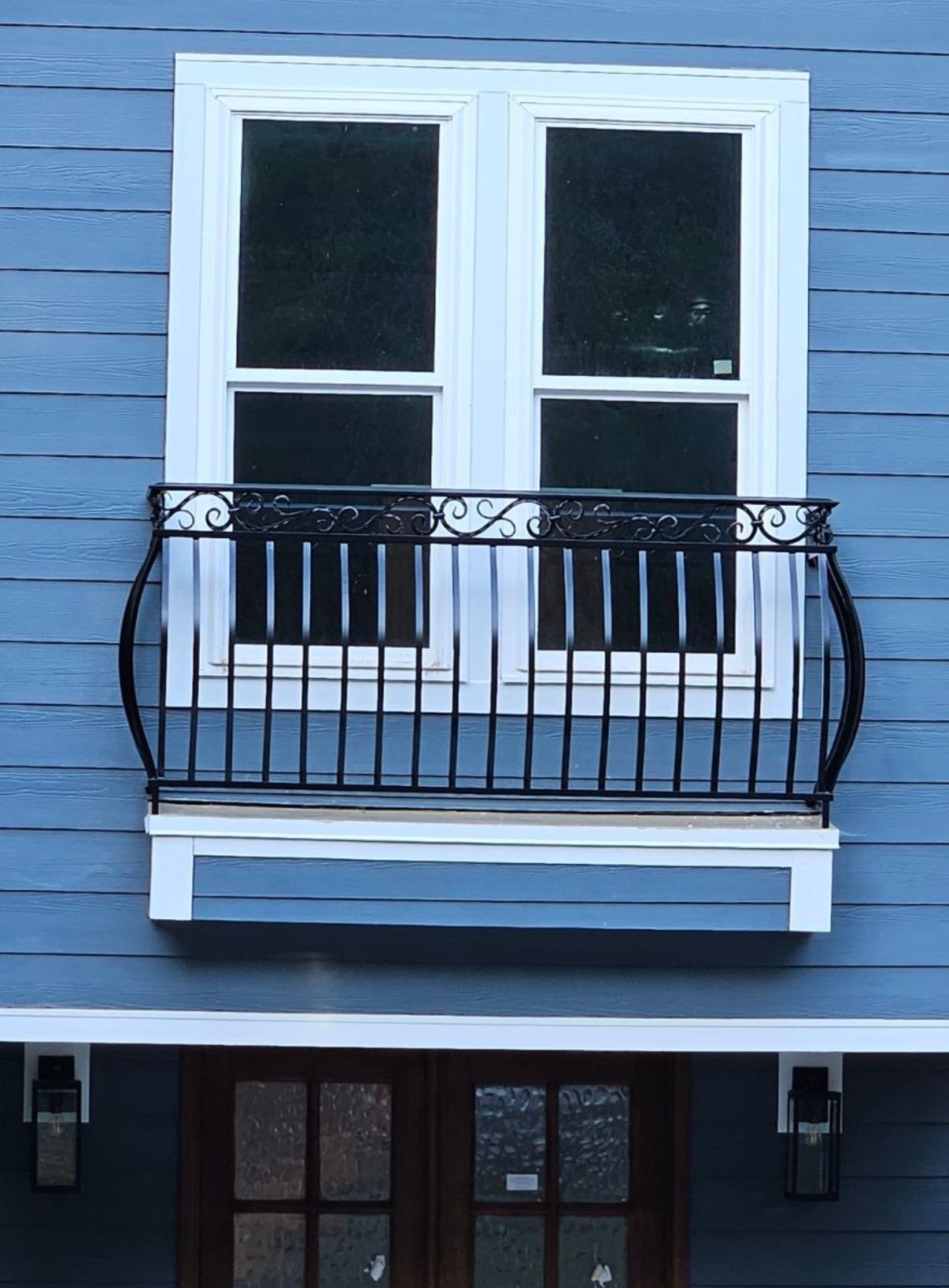 A blue house with a balcony and a window