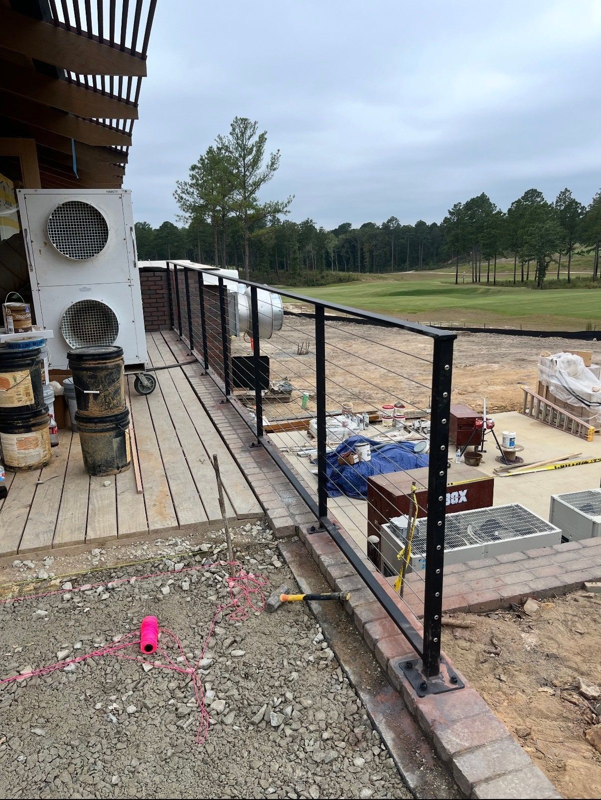 A metal railing is being installed on a balcony overlooking a golf course.