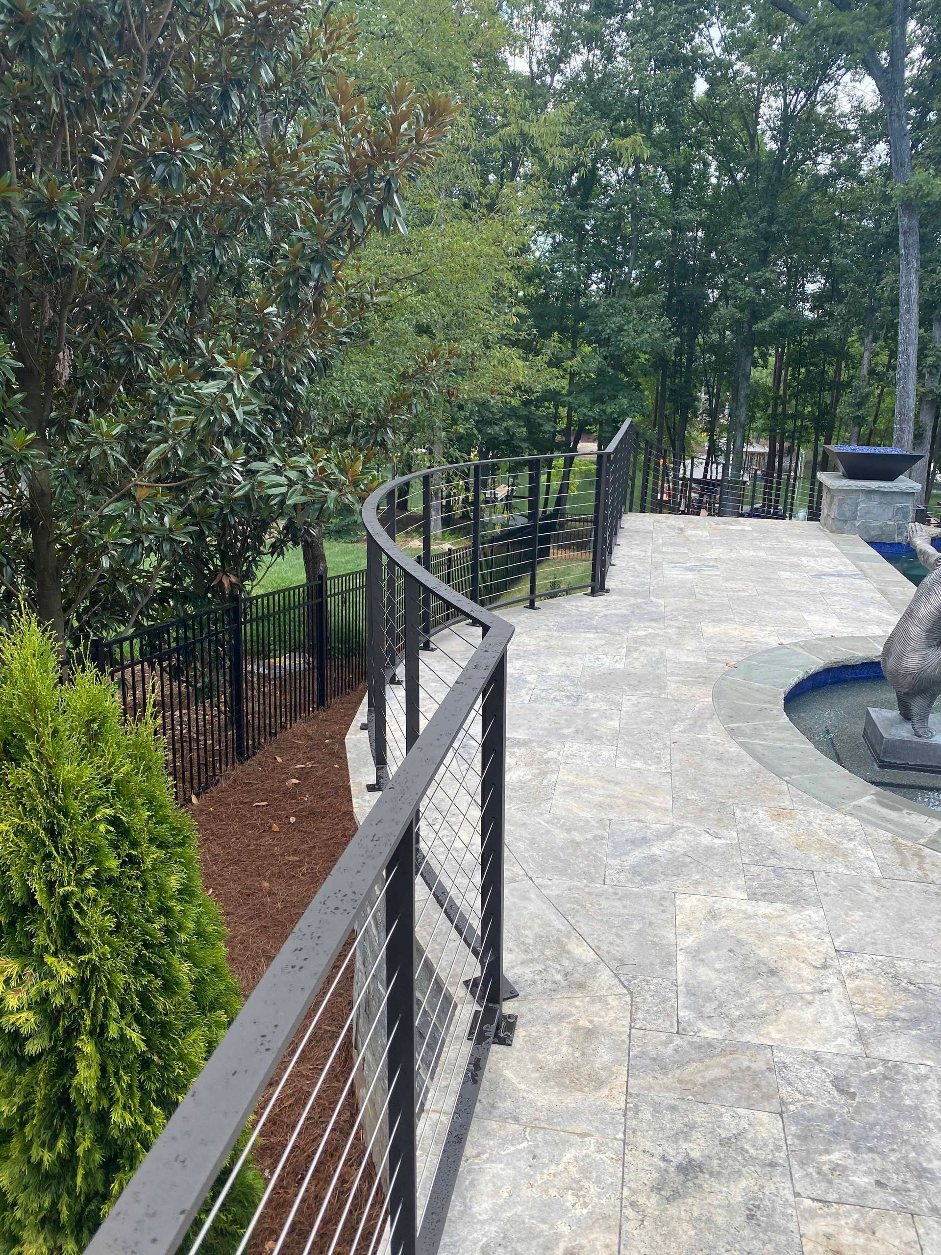 A patio with a fence and a fountain in the background.