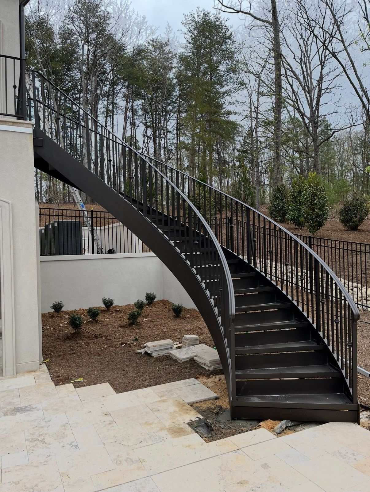 A curved staircase with a wrought iron railing in front of a house