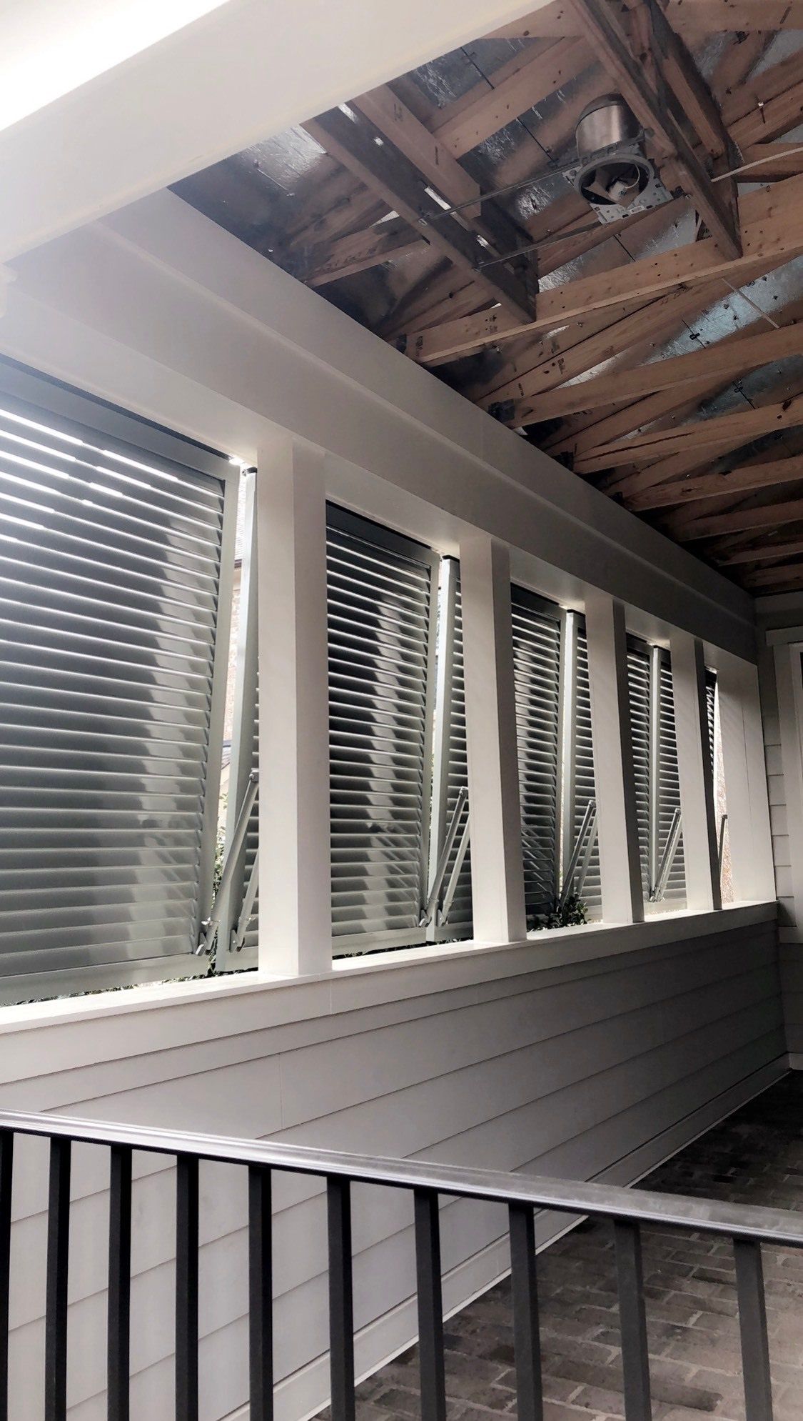 A balcony with blinds on the windows and a ceiling fan.