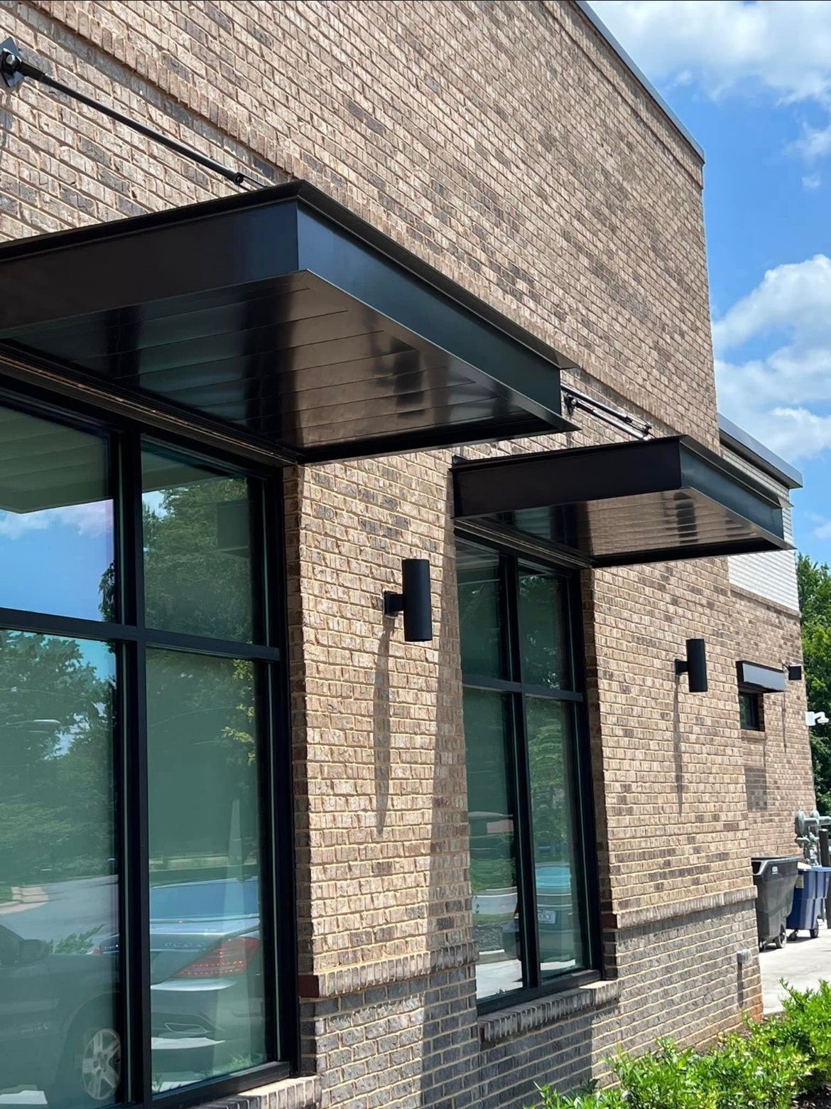 A brick building with a black awning over the windows.