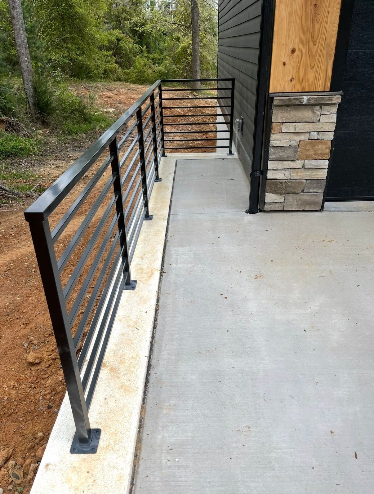 A concrete walkway with a metal railing leading to a house.