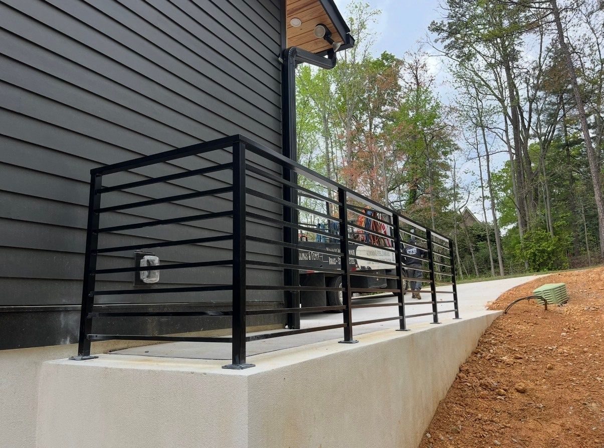 There is a black railing on the side of a house.