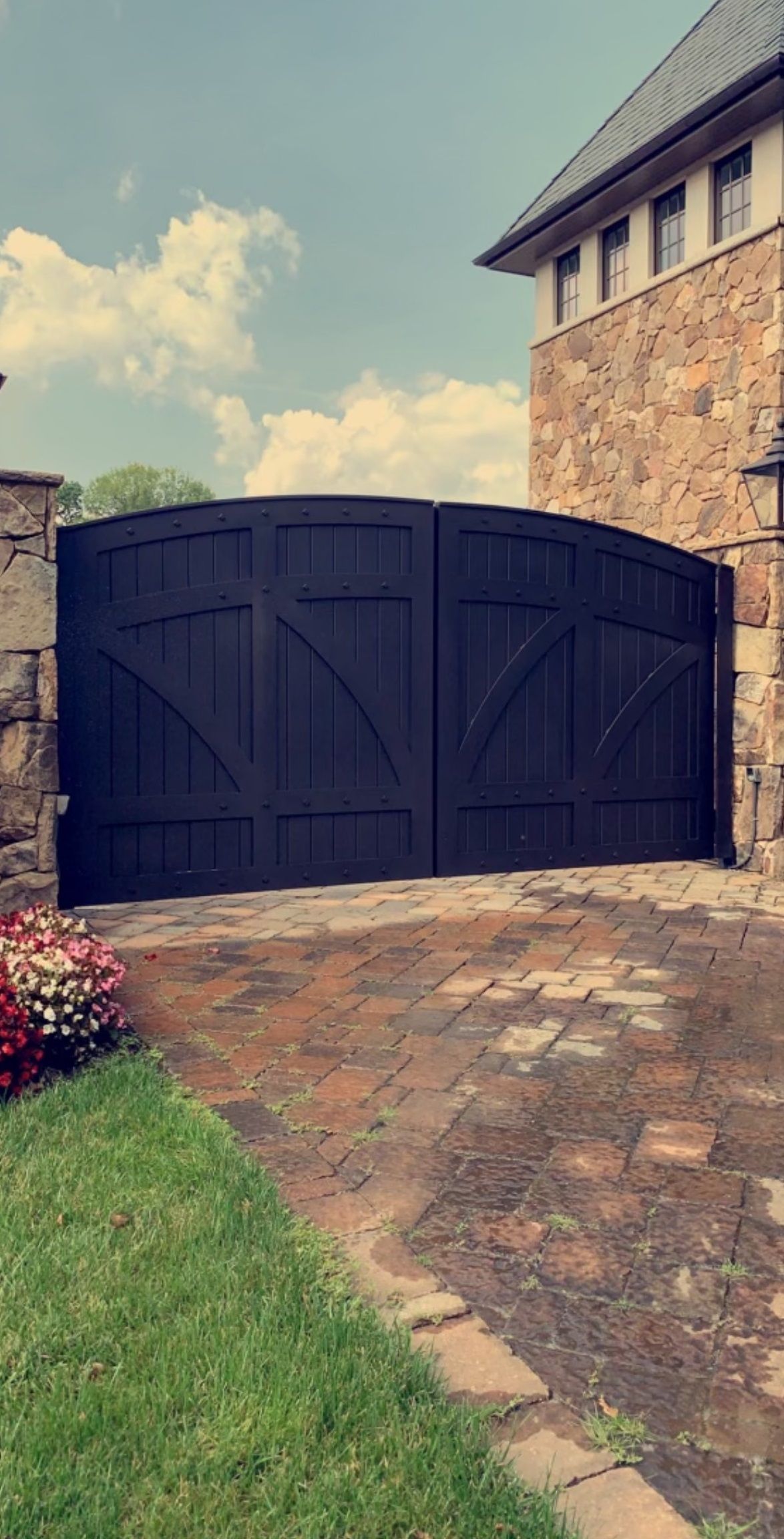 A black wooden gate is in front of a stone building.