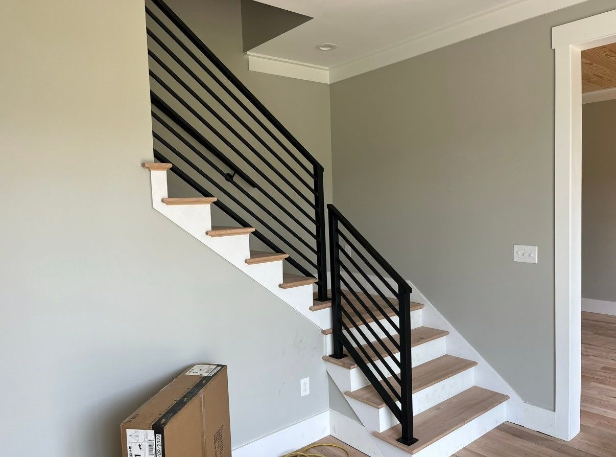 A staircase with a black railing and wooden steps in a house.