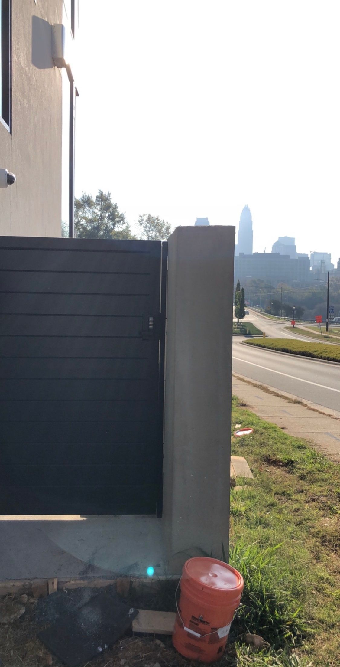 A bucket is sitting next to a gate in front of a building.