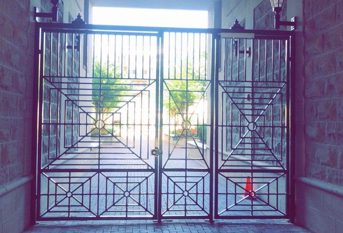 A wrought iron gate is open to a brick building.