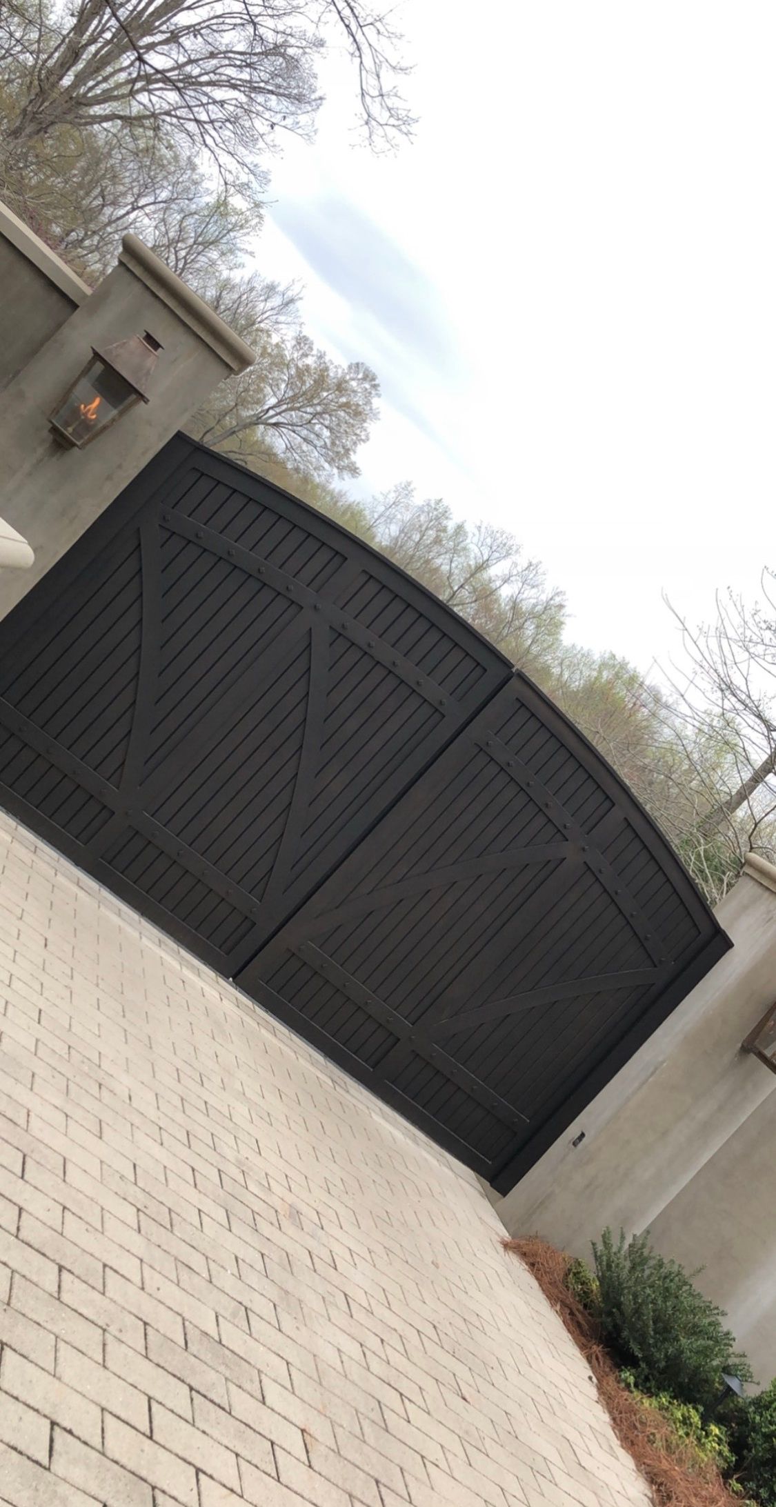 A black garage door is sitting next to a white brick wall.