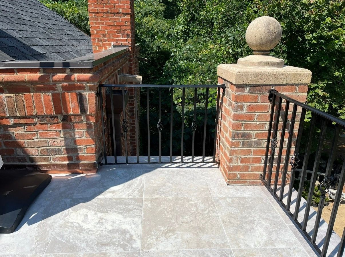 A balcony with a wrought iron railing and a brick chimney.