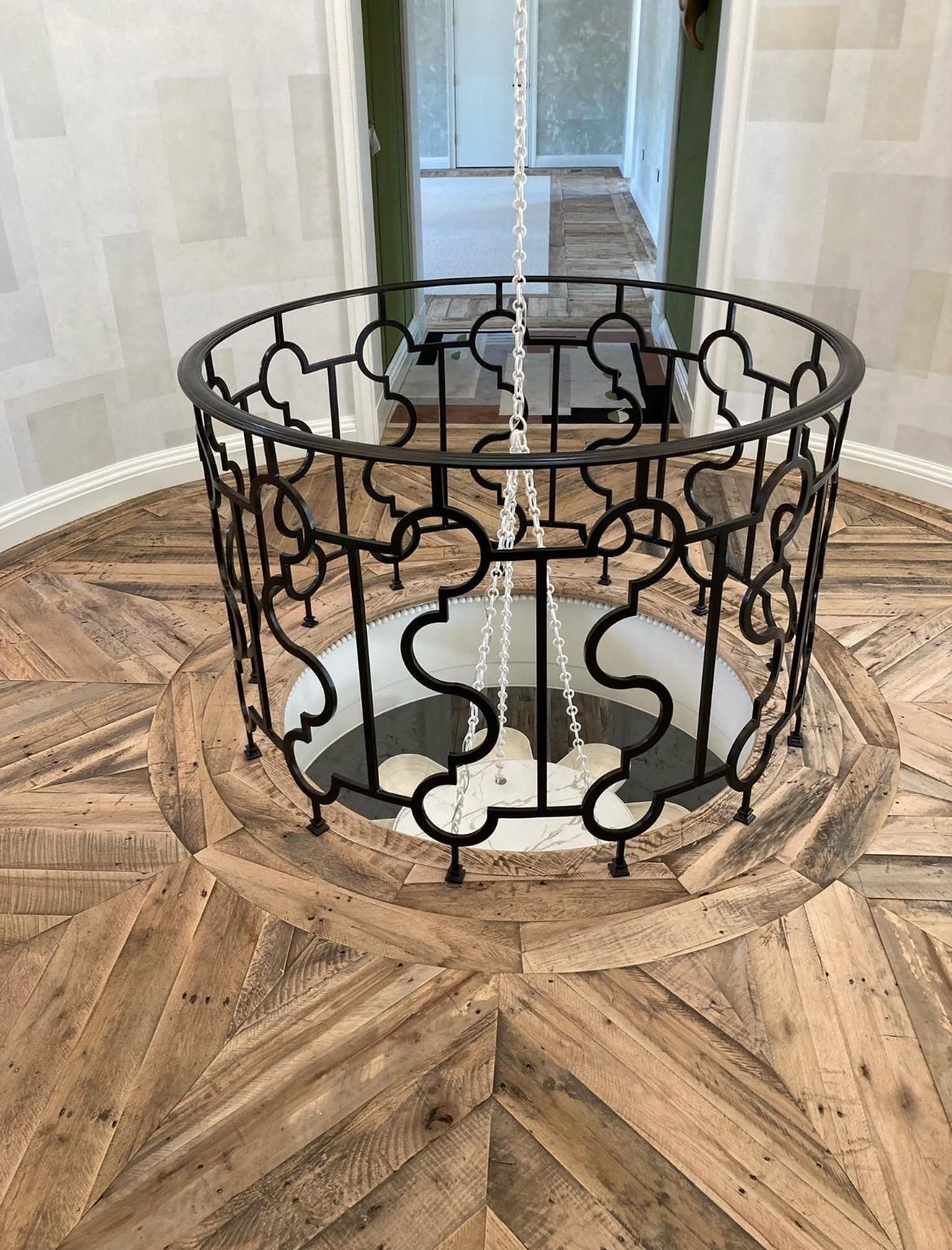 A wrought iron railing is hanging from the ceiling above a wooden floor.