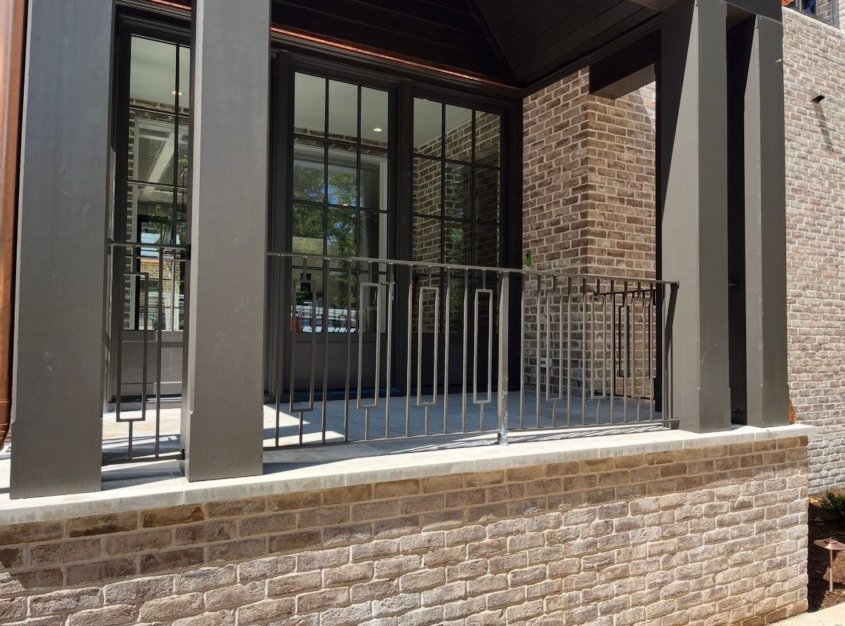 A brick building with a balcony and a wrought iron railing.