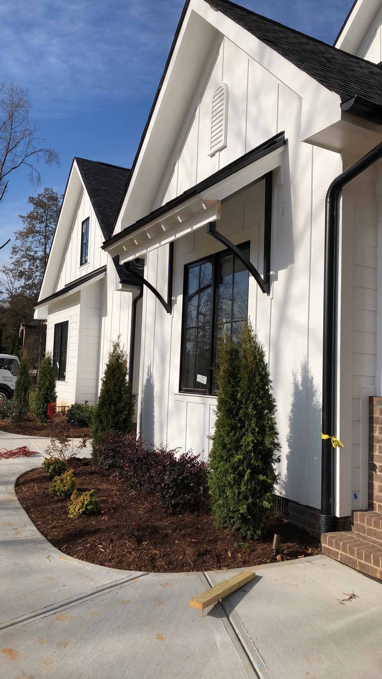 A white house with a black roof and a canopy over the front door.