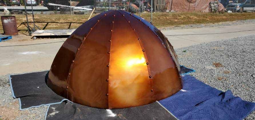 A large copper dome is sitting on top of a blue tarp.