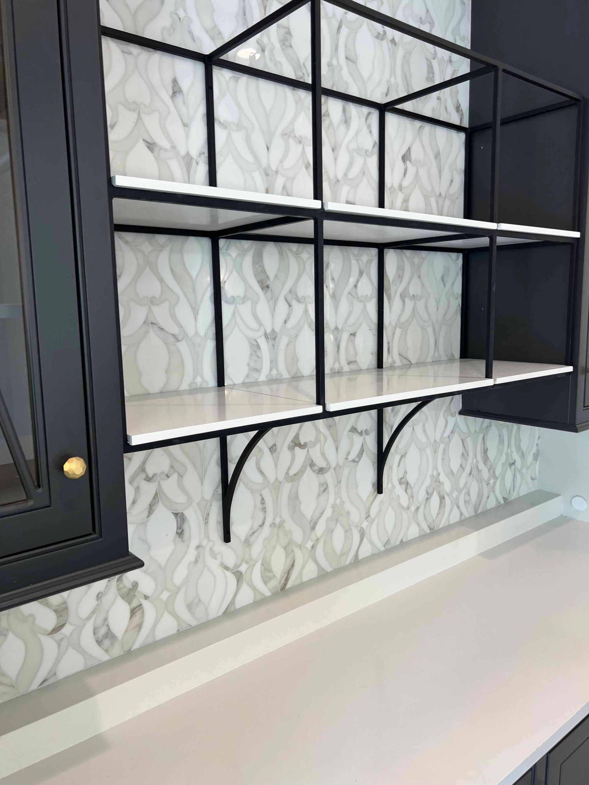 A kitchen with black cabinets and white shelves on the wall.