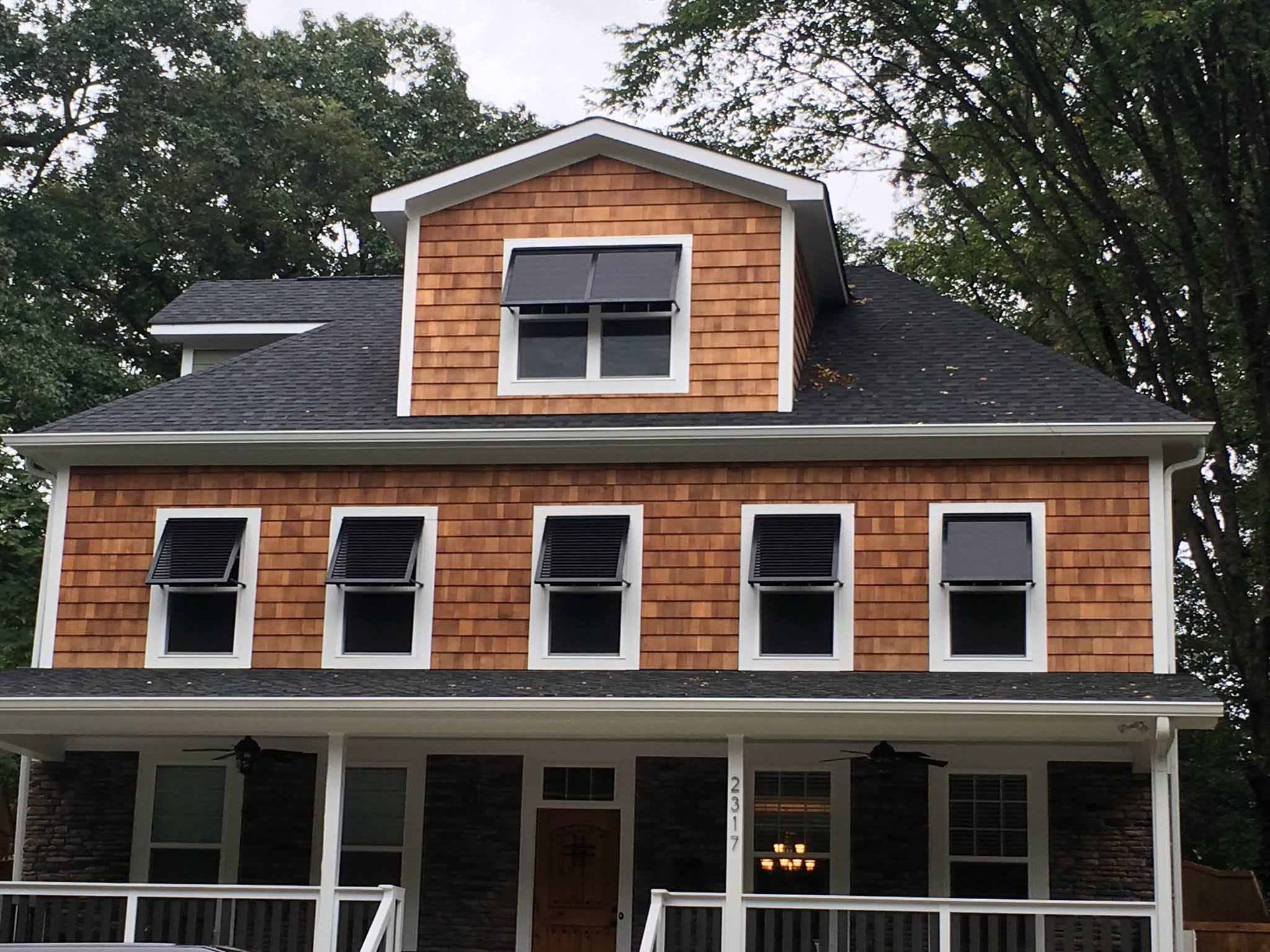 A large house with a porch and a black roof