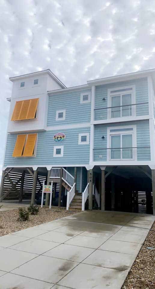 A large blue and white house with a driveway in front of it.