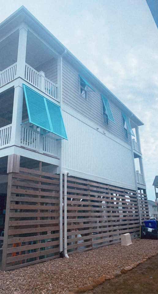A large white house with a blue awning on the side of it.