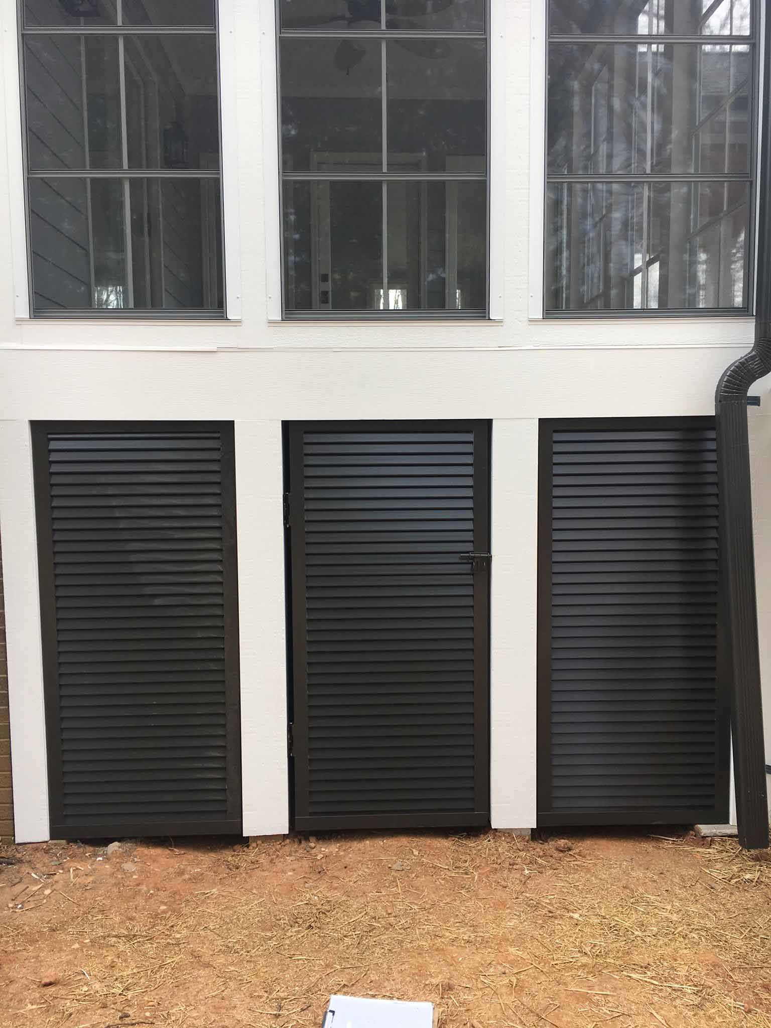 A white building with black shutters on the doors and windows.