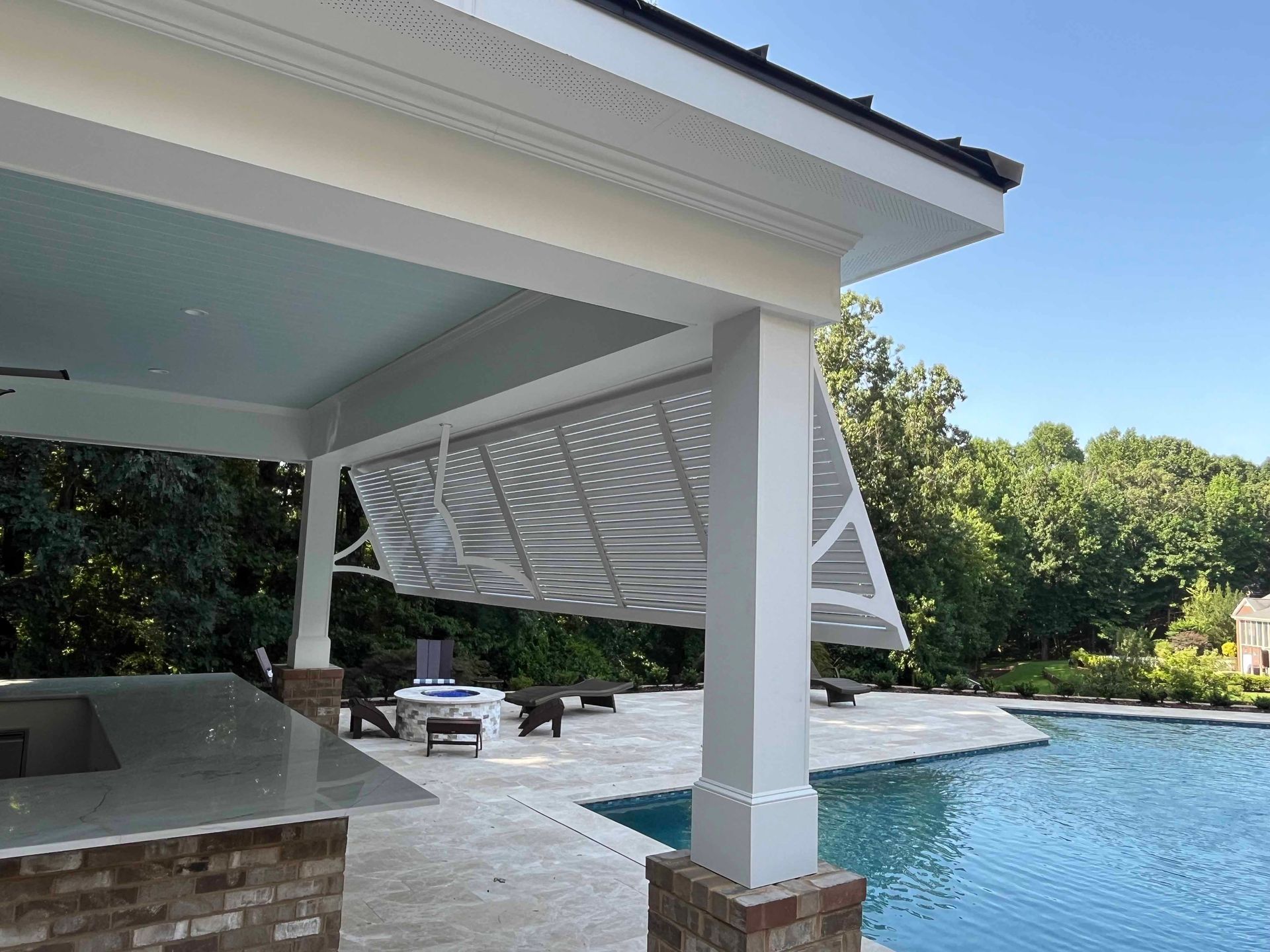 There is a large swimming pool in the backyard with a pergola over it.