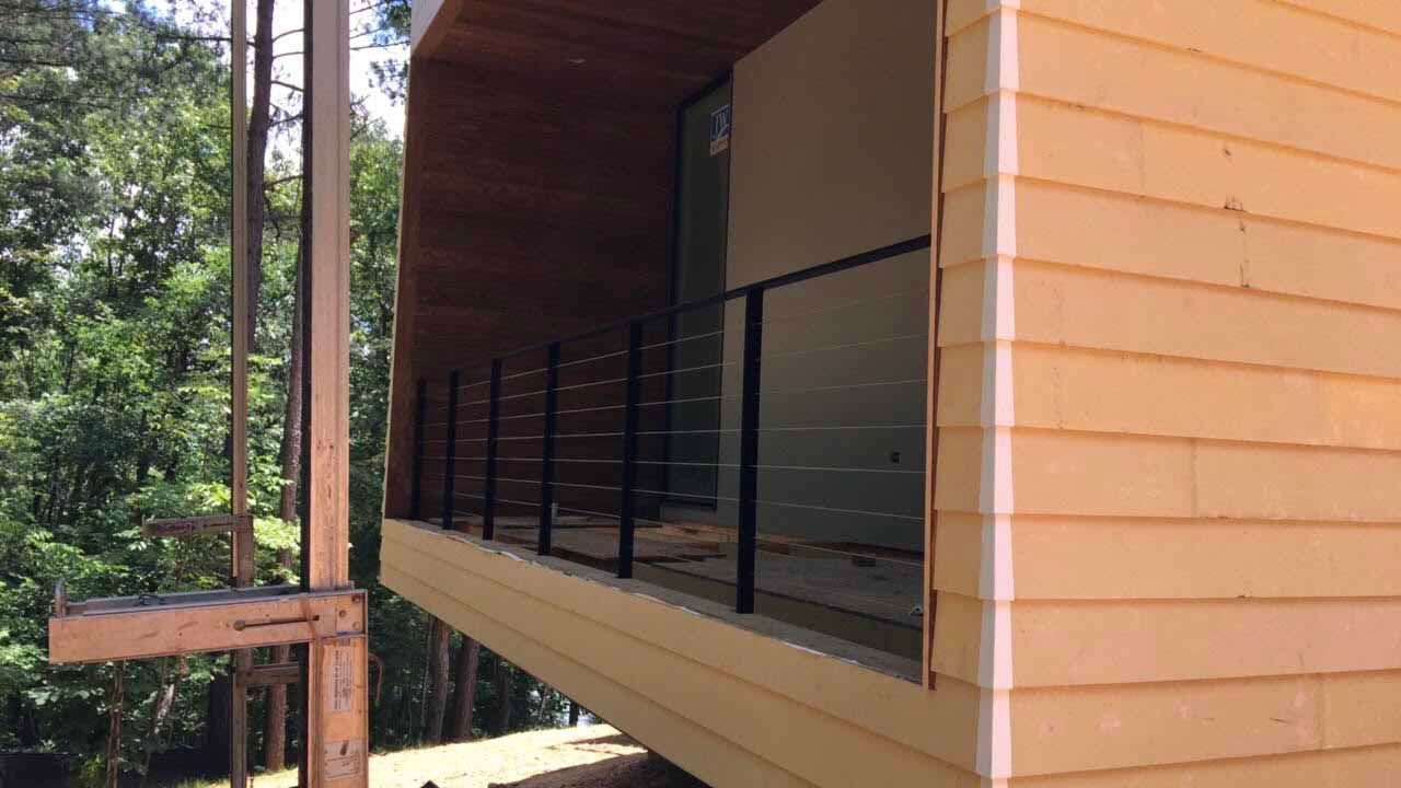 A wooden house with a balcony and trees in the background.