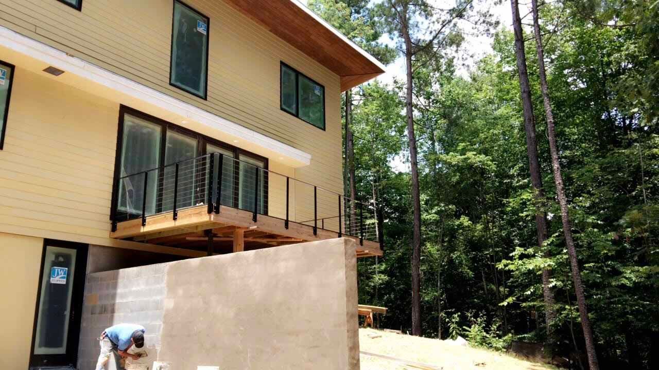 A man is working on a wall in front of a house.
