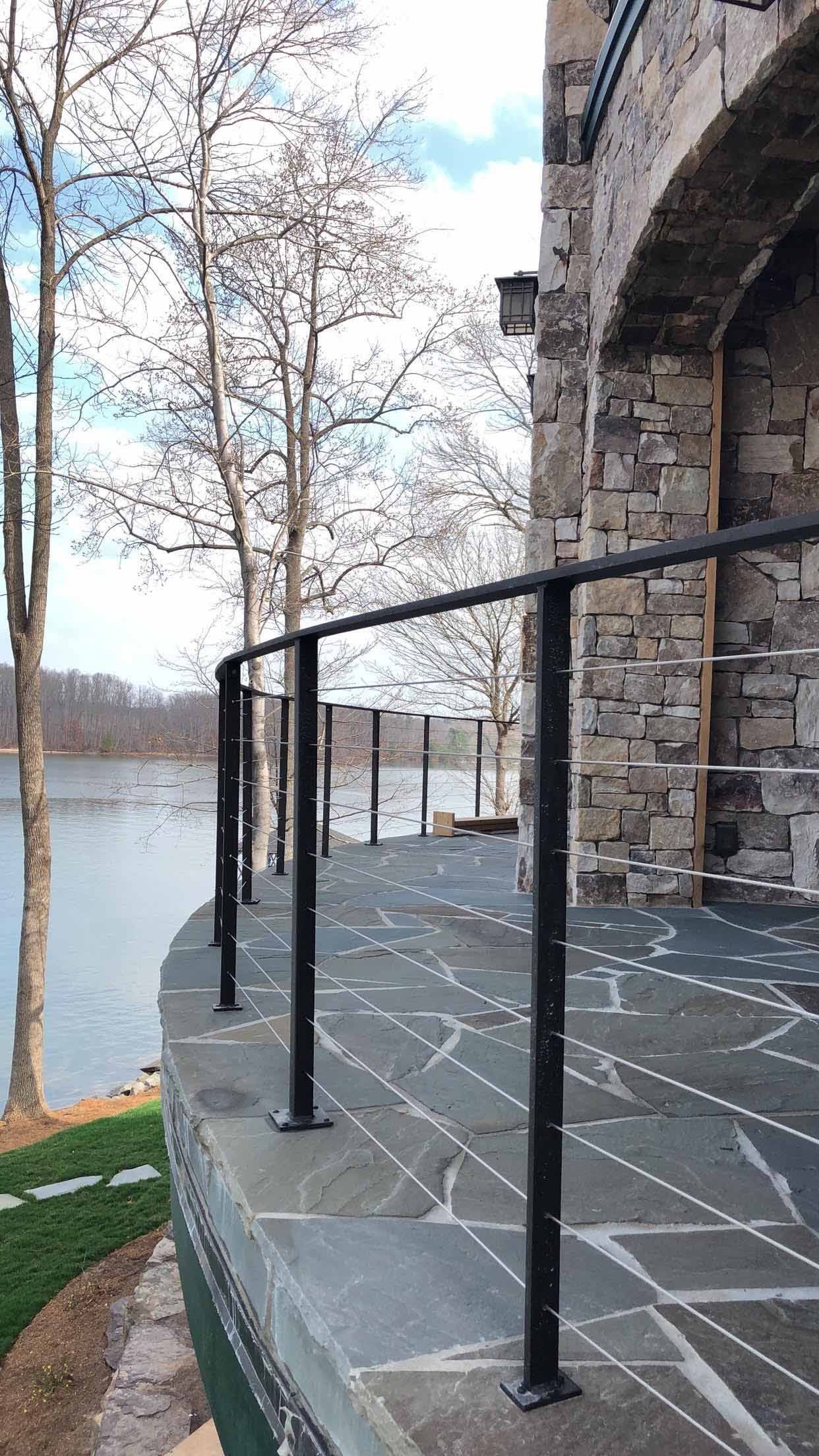 A stone walkway with a railing leading to a lake.