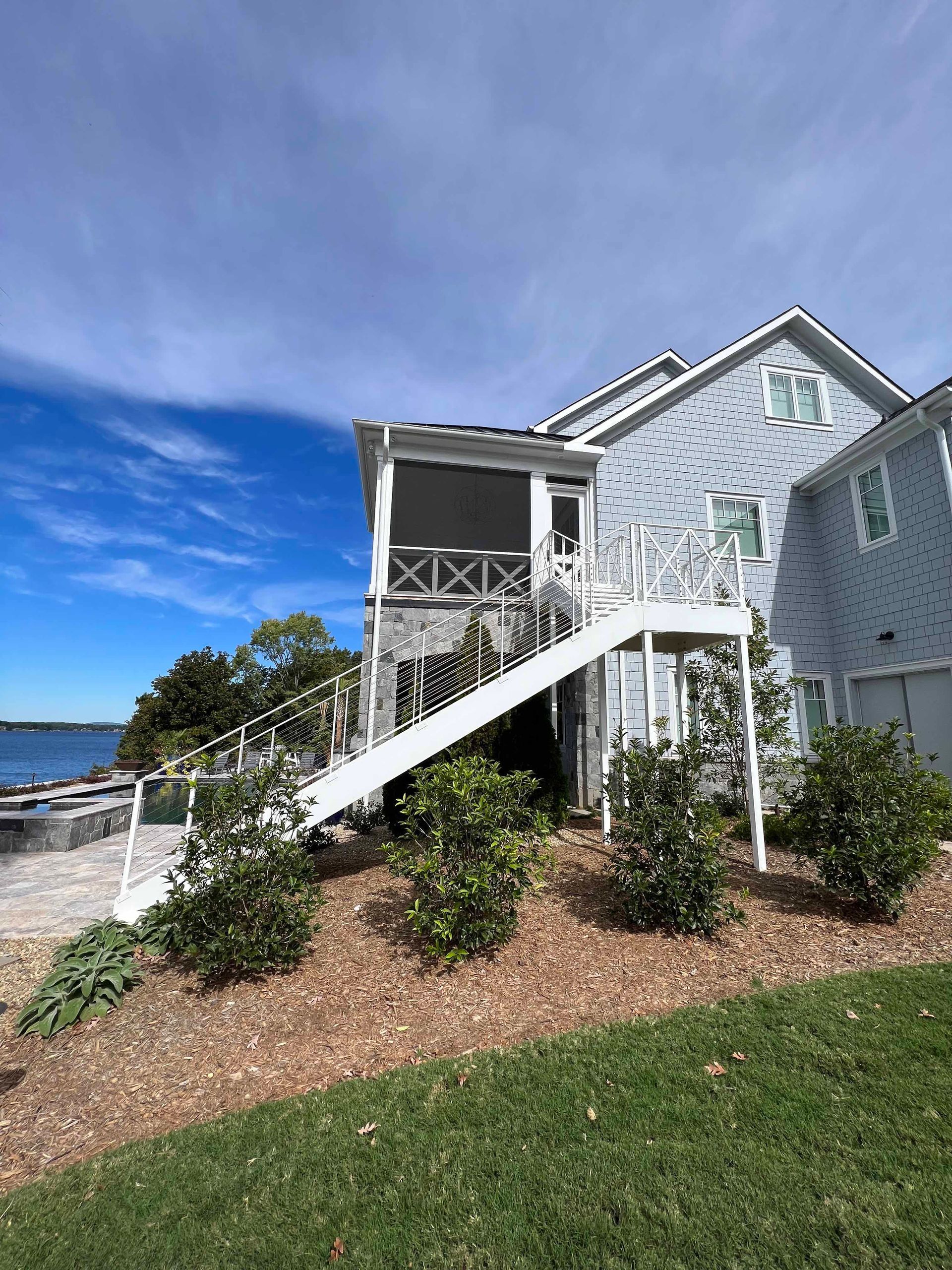 A large white house with stairs leading up to the second floor.