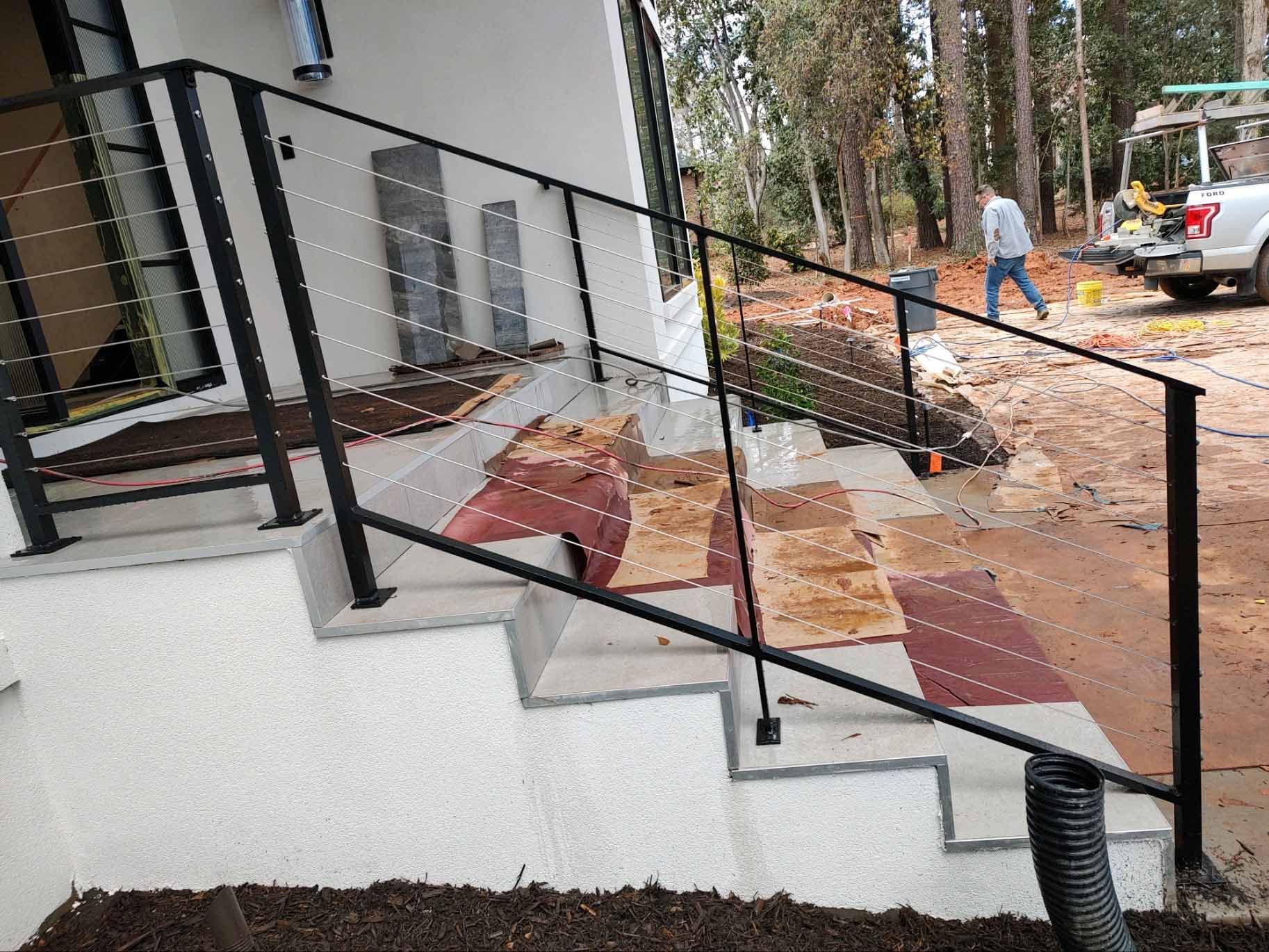 A black railing is being installed on the stairs of a house.
