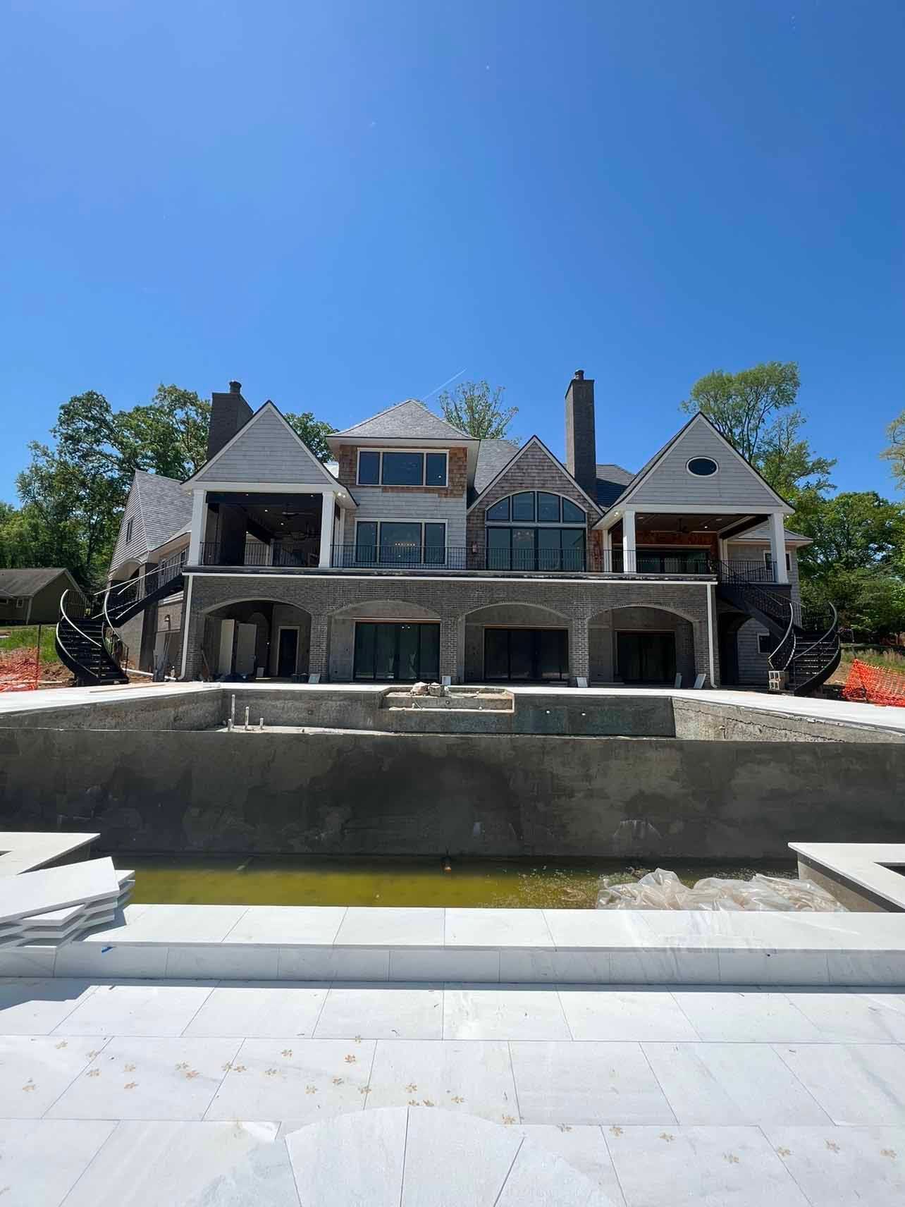 A large house is being built with a swimming pool in front of it.