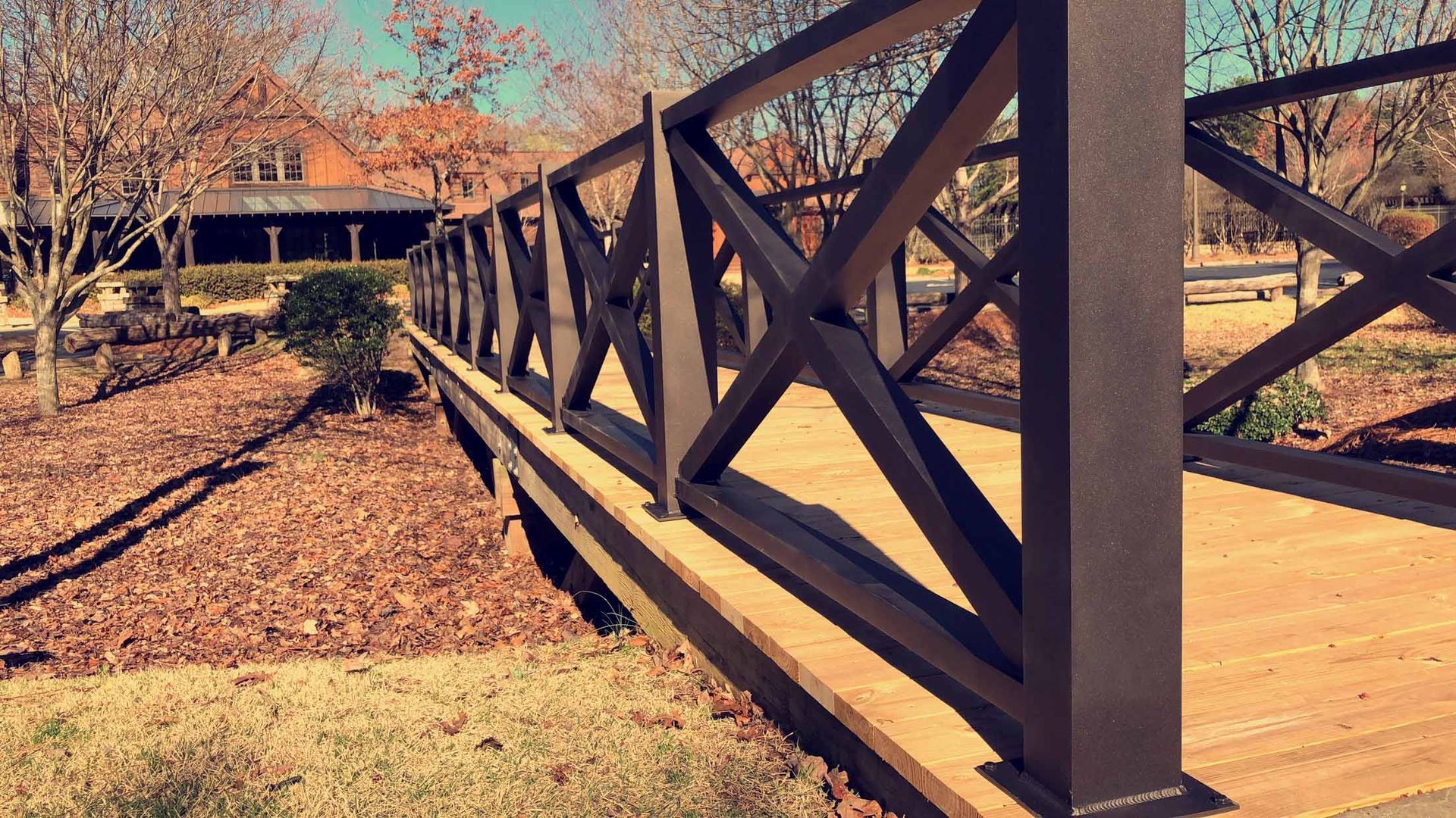 A wooden bridge with a metal railing in a park.