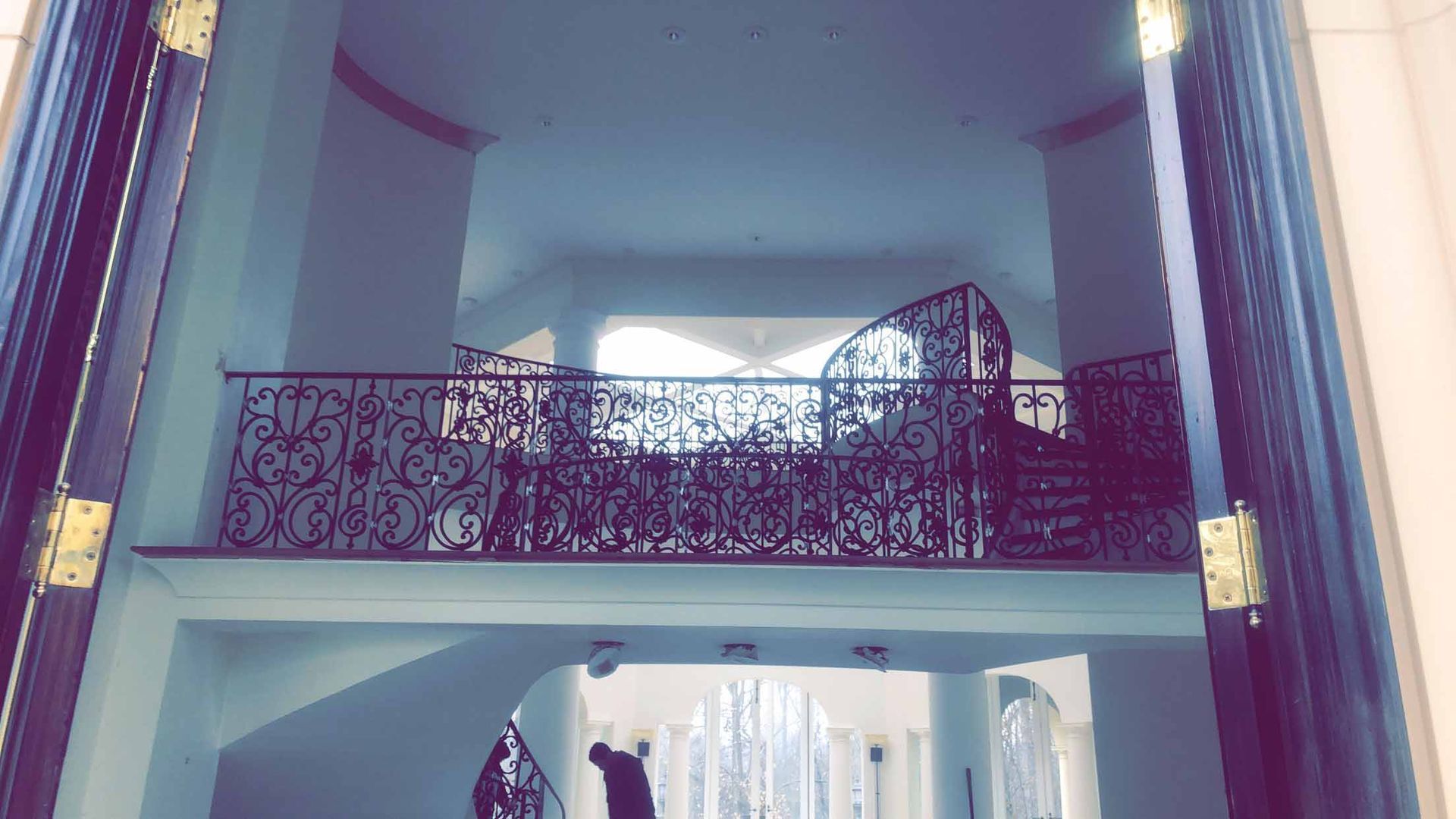 A staircase in a house with a balcony and a chandelier.
