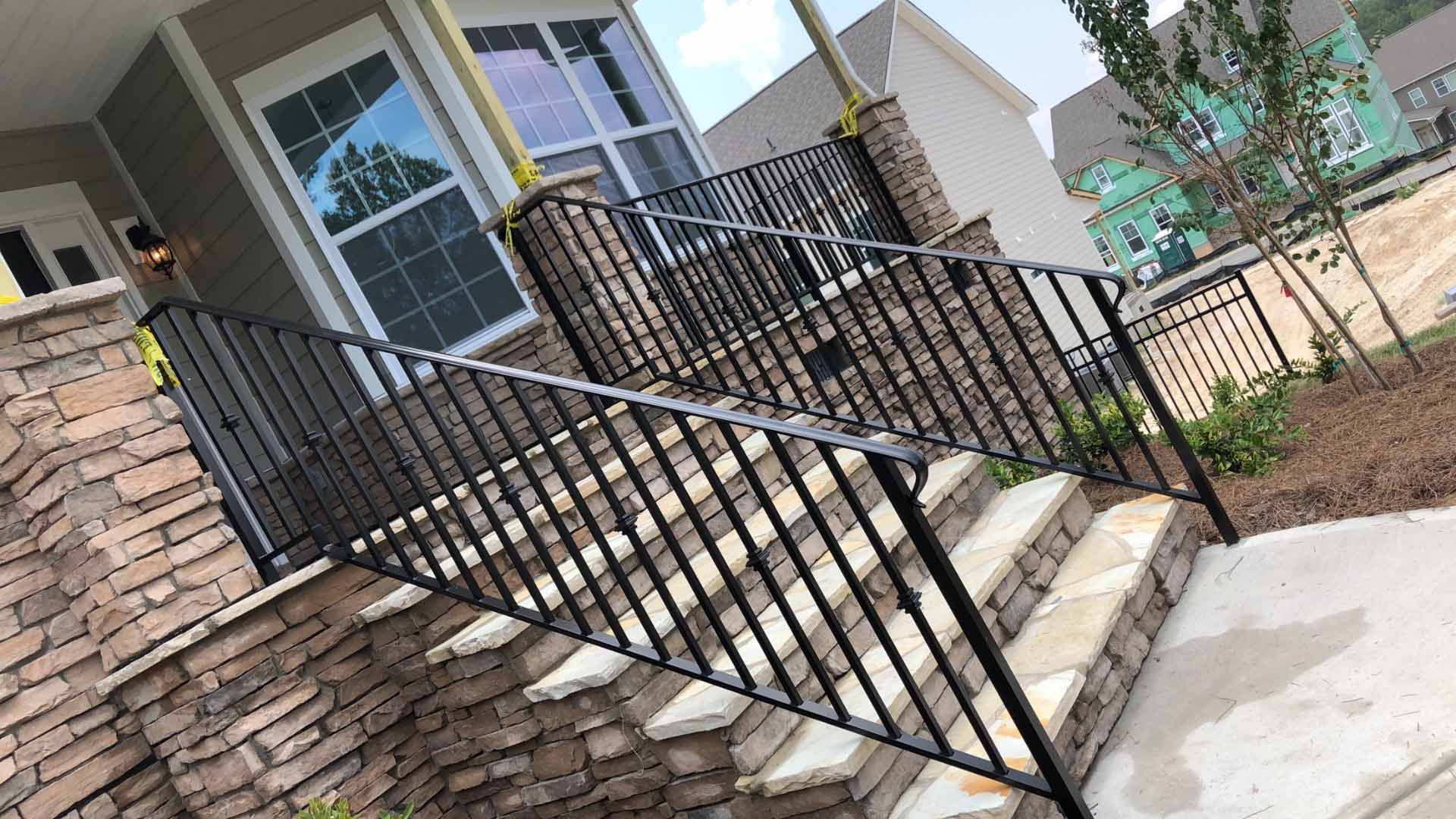 A wrought iron railing is surrounding a set of stairs leading up to a house.