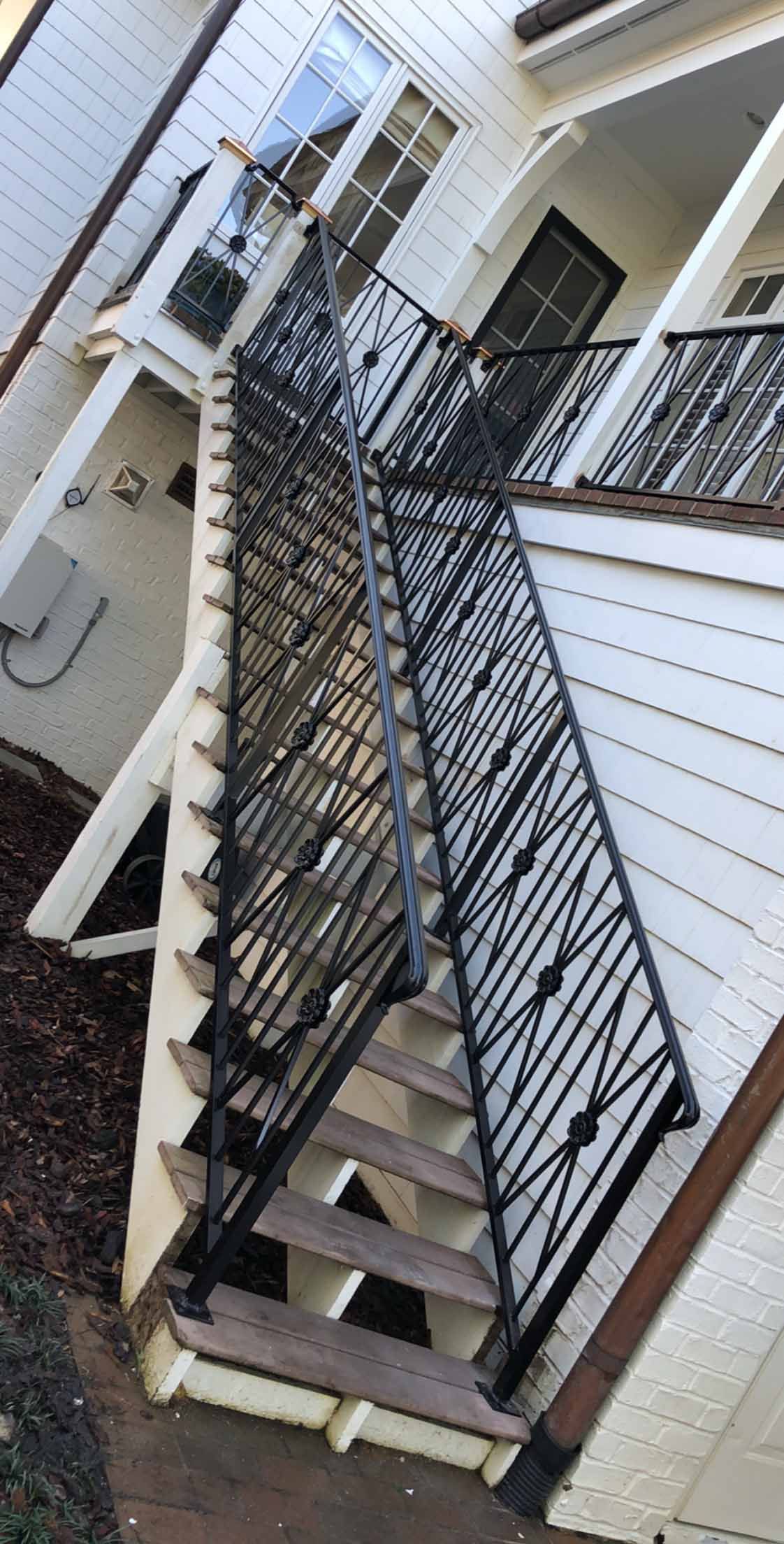 A set of stairs leading up to a house with a wrought iron railing.