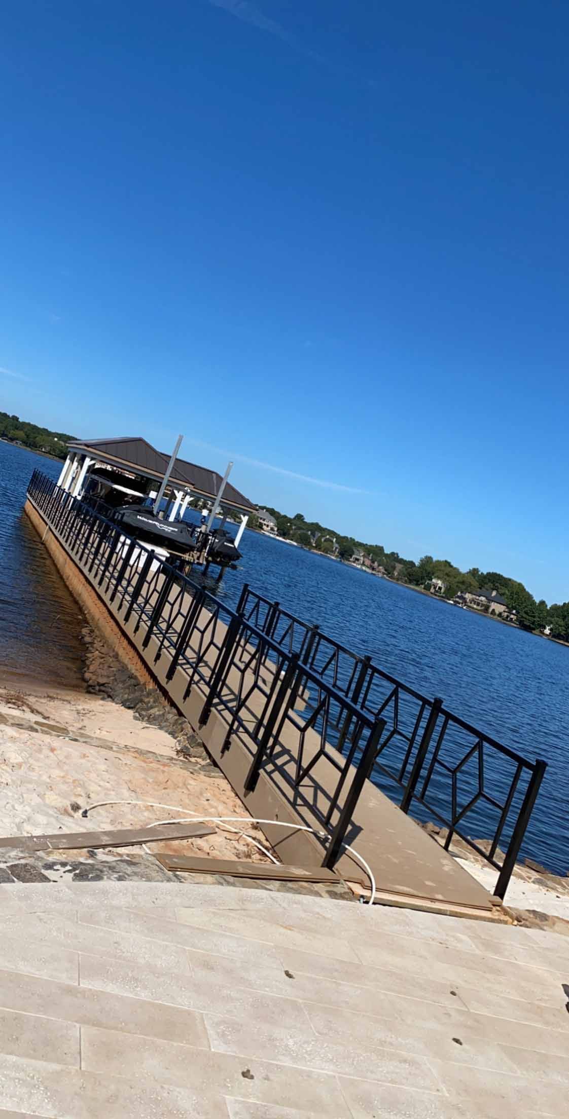 A dock with a fence leading to a body of water.