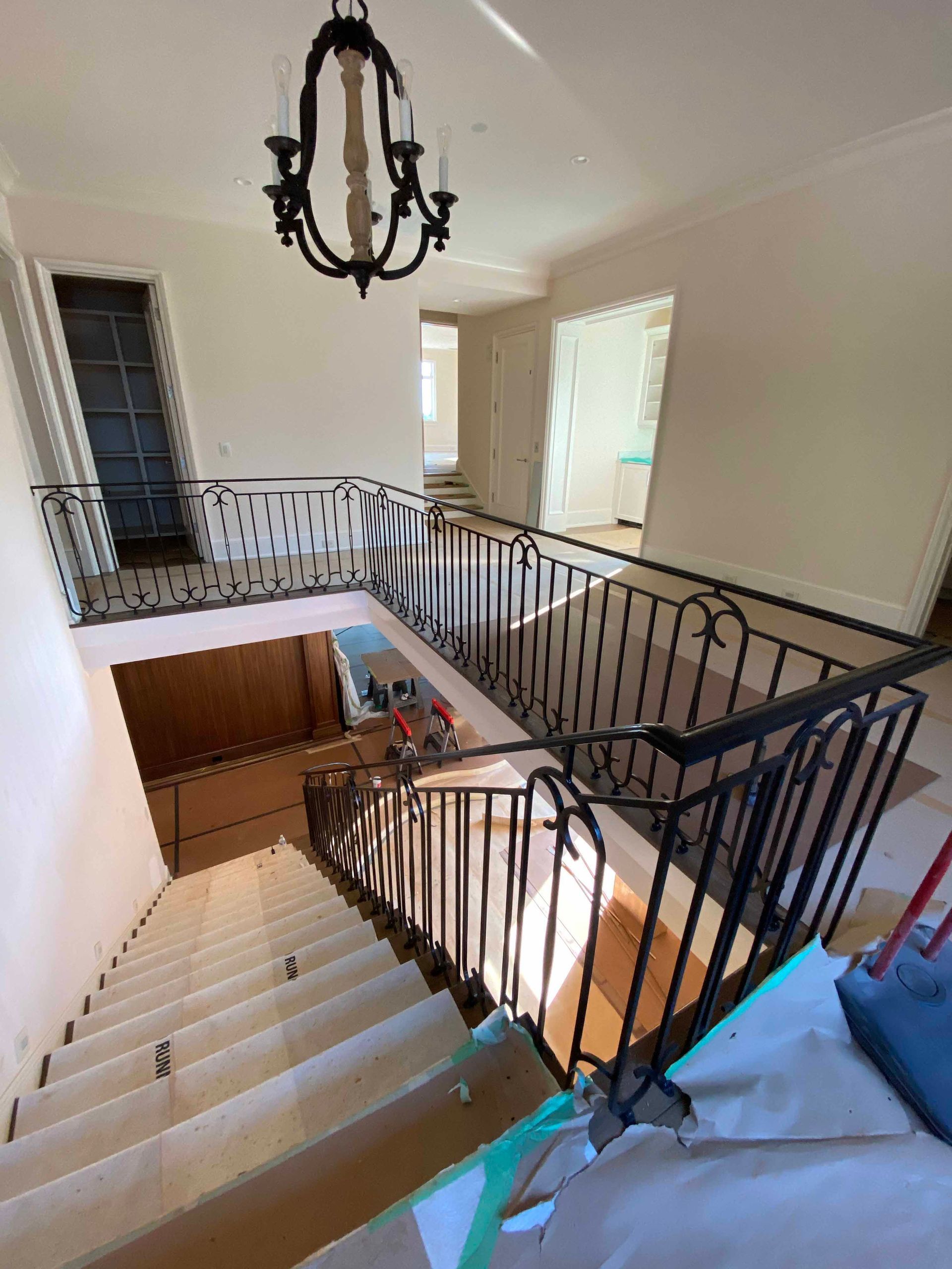 A staircase with a wrought iron railing and a chandelier hanging from the ceiling.
