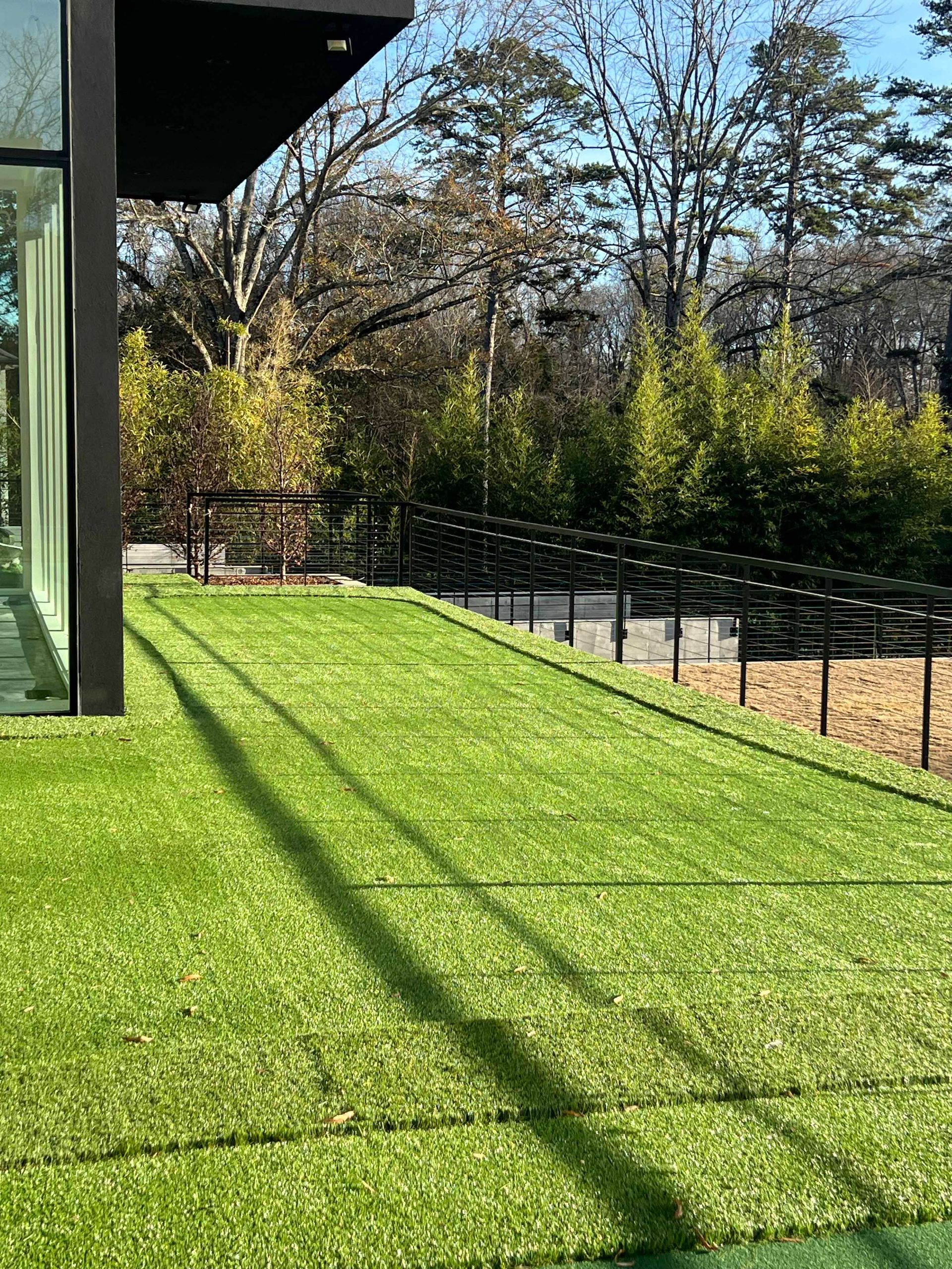 A lush green lawn in front of a building with trees in the background.